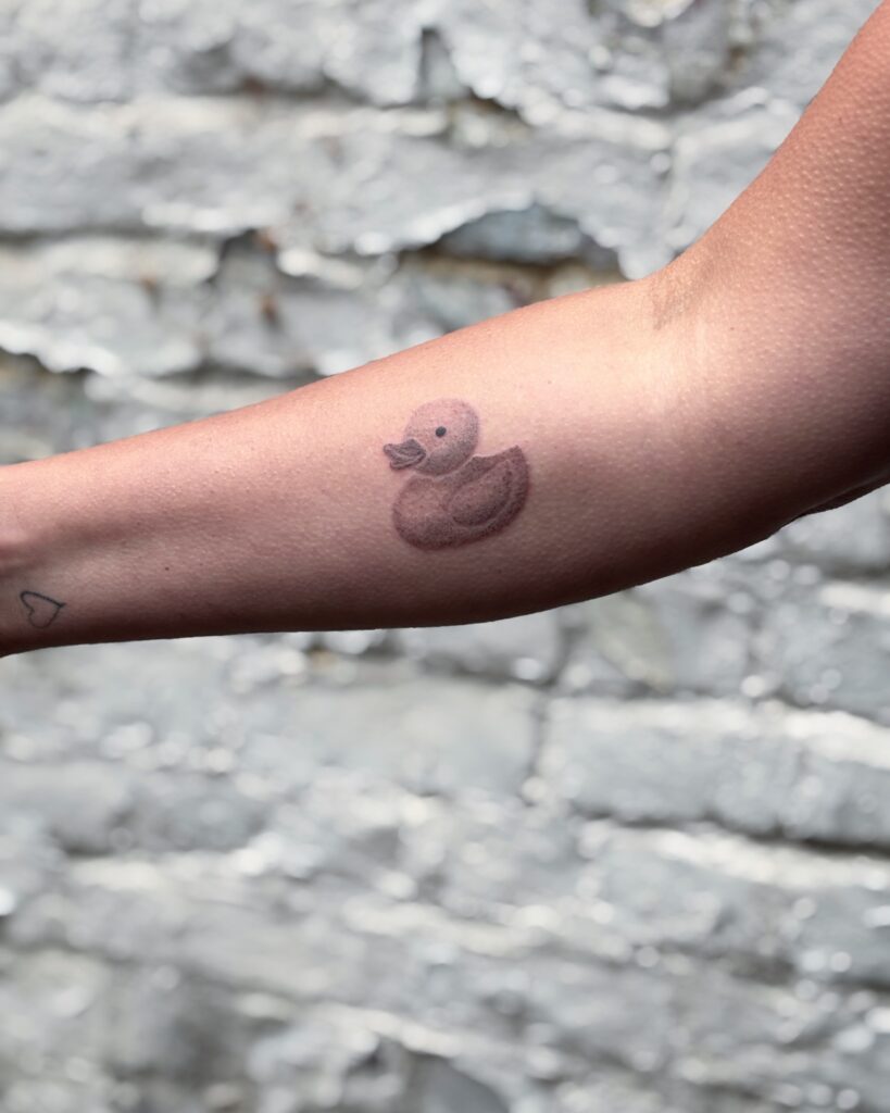 image de portefoilio, tatouage fin d'un canard en plastique sur l'avant-bras, technique d'ombrage
